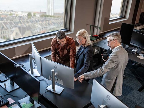 Tre IT-konsulenter står og peger på en computerskærm